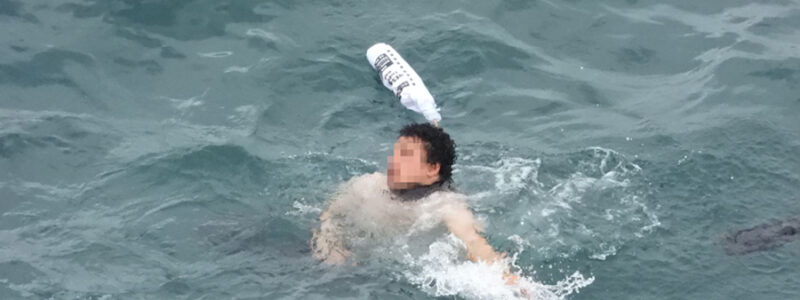 Individual with a pixelated face who has fallen into the sea without a life jacket